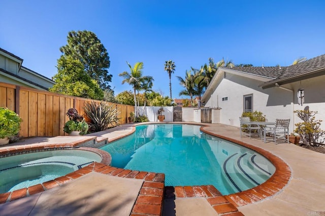 view of pool with a pool with connected hot tub, a patio area, and a fenced backyard