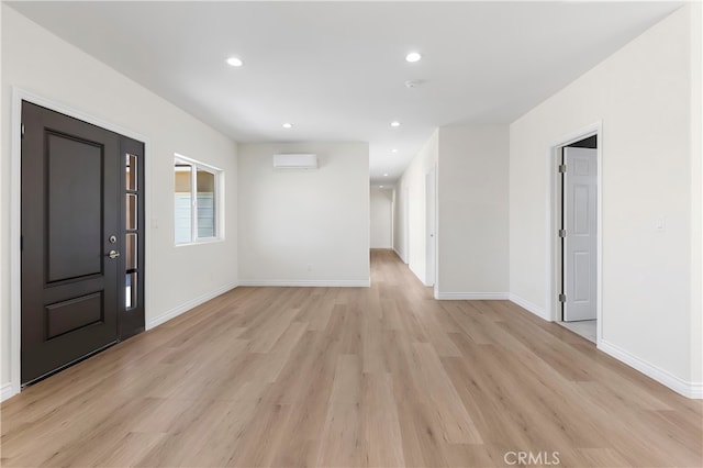 interior space featuring recessed lighting, light wood-style floors, baseboards, and a wall mounted air conditioner