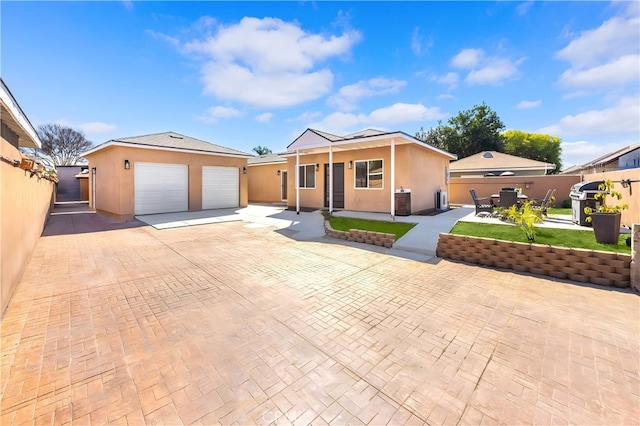 single story home with stucco siding, a detached garage, an outbuilding, and fence