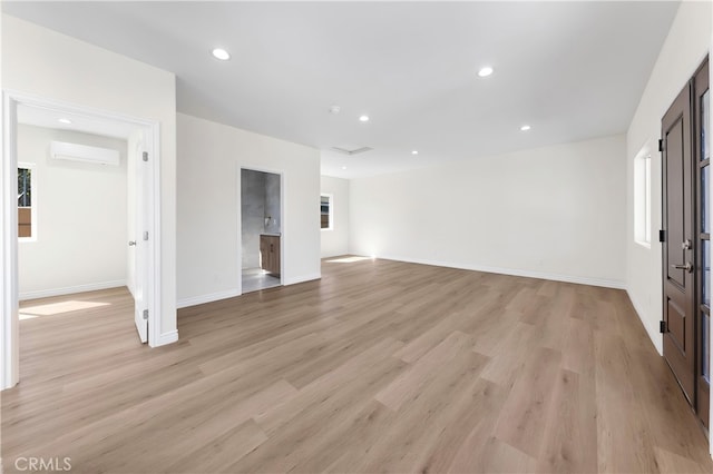 spare room with a wall mounted air conditioner, baseboards, recessed lighting, and light wood finished floors