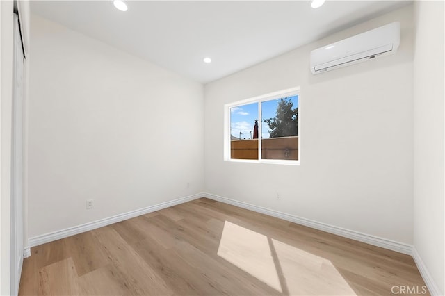 empty room with recessed lighting, baseboards, wood finished floors, and a wall unit AC