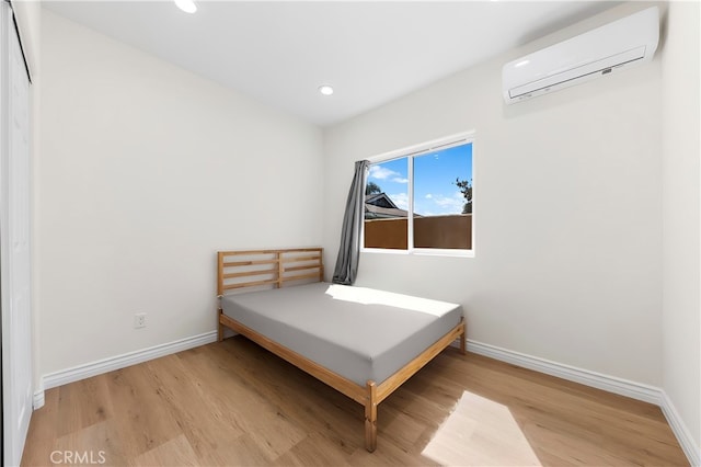 bedroom with recessed lighting, baseboards, an AC wall unit, and wood finished floors