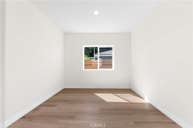 empty room featuring recessed lighting, baseboards, and wood finished floors