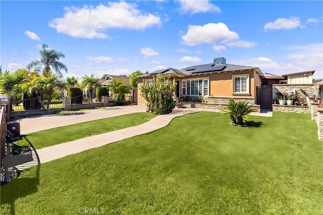 back of house with solar panels, fence, concrete driveway, a lawn, and a gate