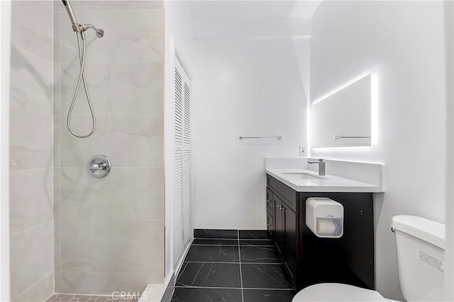 bathroom featuring vanity, toilet, and tiled shower