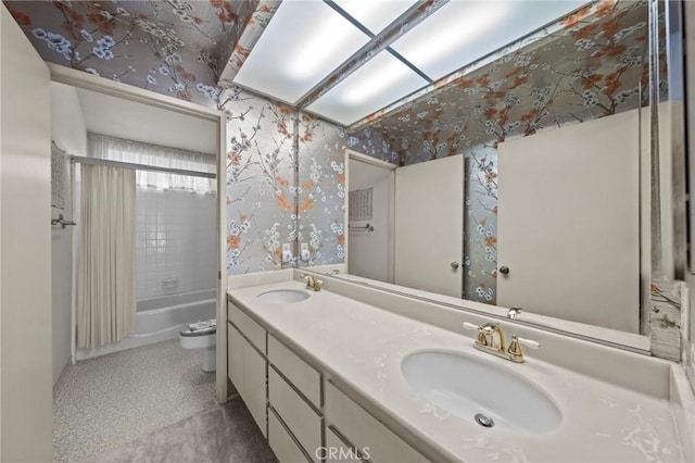 full bath featuring a sink, toilet, double vanity, and wallpapered walls