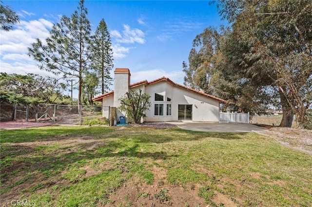 rear view of property featuring a patio area, stucco siding, a lawn, and fence