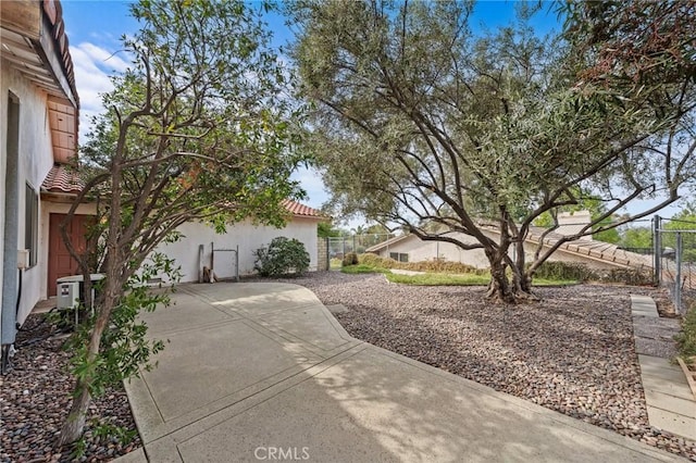 exterior space with stucco siding, a tiled roof, a patio, and fence