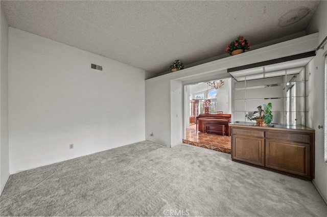 unfurnished room with visible vents, carpet floors, and a textured ceiling