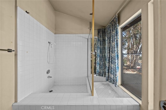 full bathroom with vaulted ceiling and tiled shower