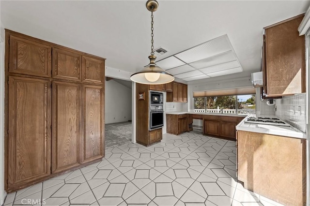 kitchen with oven, visible vents, brown cabinetry, light countertops, and white gas cooktop