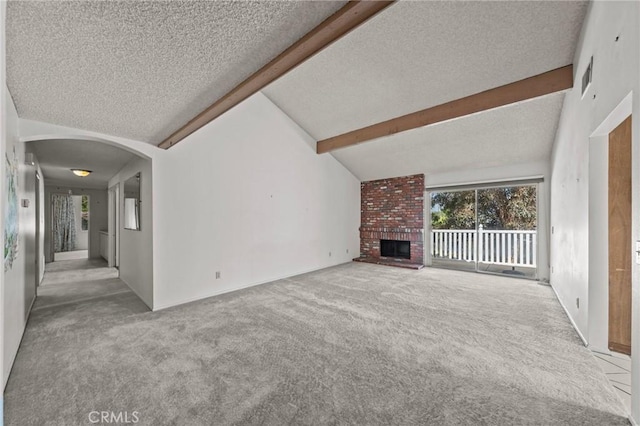 unfurnished living room with carpet, lofted ceiling with beams, arched walkways, a textured ceiling, and a brick fireplace