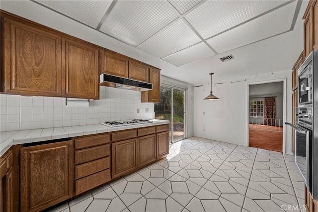 kitchen featuring under cabinet range hood, visible vents, appliances with stainless steel finishes, and brown cabinetry