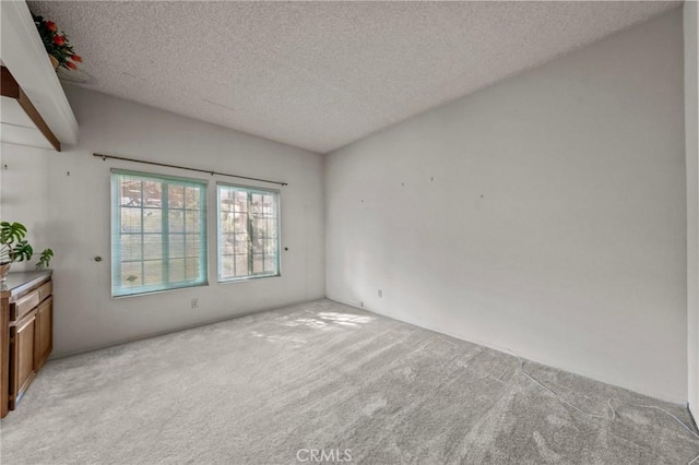 empty room with light colored carpet and a textured ceiling