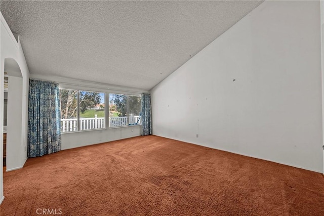 empty room with arched walkways, vaulted ceiling, a textured ceiling, and carpet floors