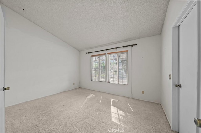 spare room with carpet flooring, a textured ceiling, and lofted ceiling