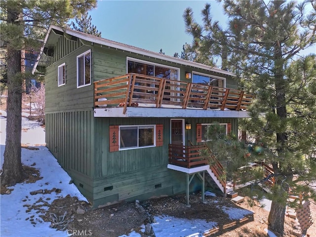 rear view of house with stairway, a wooden deck, and crawl space