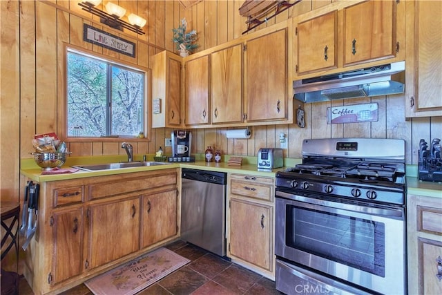 kitchen featuring light countertops, brown cabinets, appliances with stainless steel finishes, under cabinet range hood, and a sink