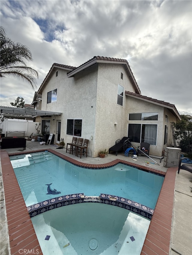 view of pool featuring a patio, fence, and a pool with connected hot tub