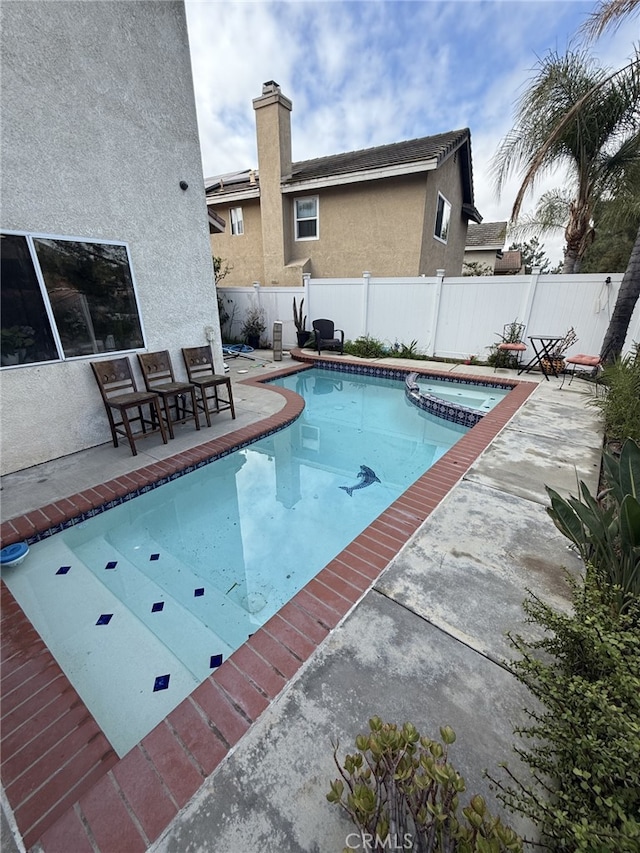 view of swimming pool featuring a patio area, a pool with connected hot tub, and a fenced backyard