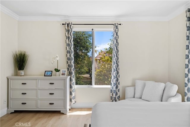 bedroom with multiple windows, light wood-style floors, baseboards, and ornamental molding