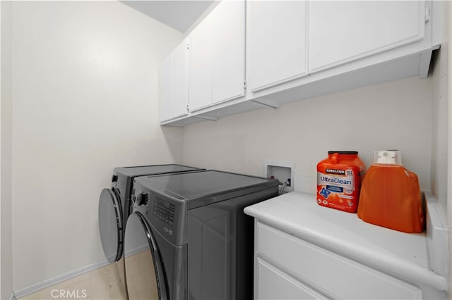 washroom with baseboards, cabinet space, and independent washer and dryer