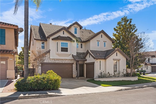 view of property with a tile roof, stucco siding, a garage, stone siding, and driveway