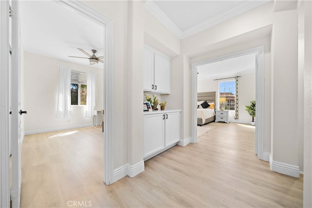 corridor featuring a wealth of natural light, baseboards, light wood finished floors, and ornamental molding