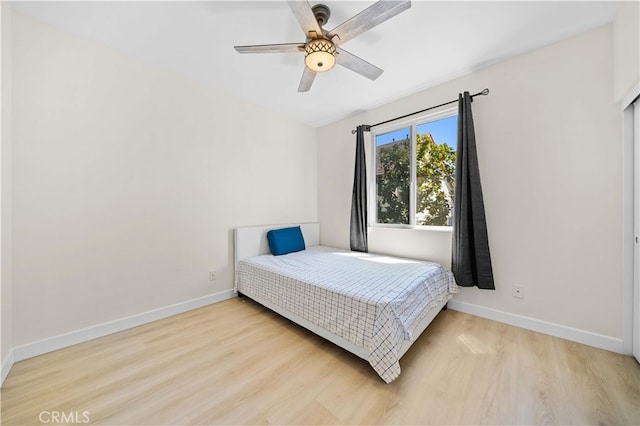 bedroom featuring baseboards, wood finished floors, and a ceiling fan