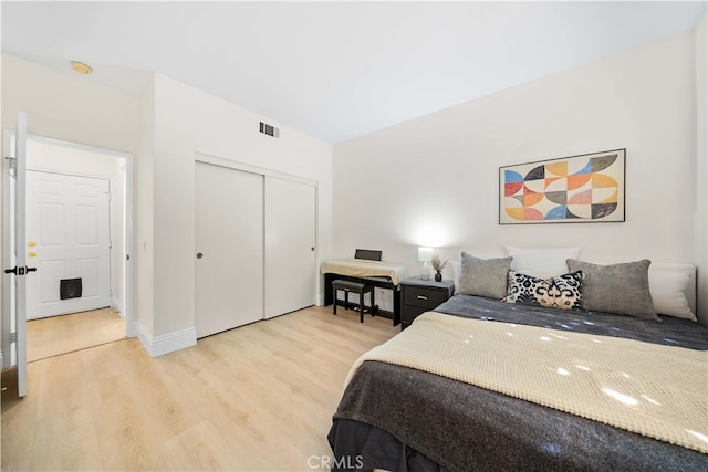 bedroom featuring a closet, baseboards, visible vents, and light wood finished floors