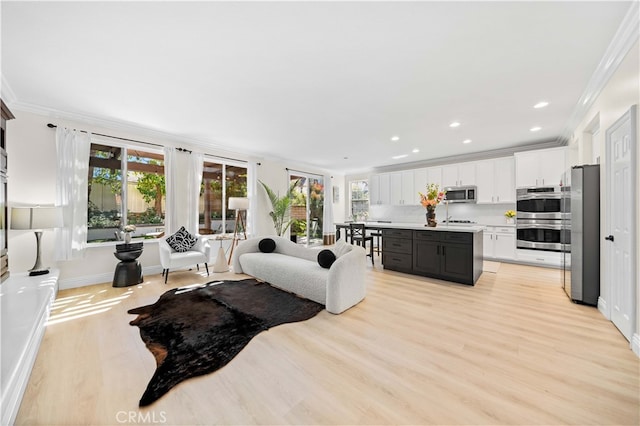 living room with recessed lighting, a healthy amount of sunlight, light wood-type flooring, and crown molding