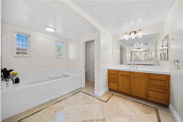 full bathroom featuring a bath, a textured ceiling, vanity, and baseboards