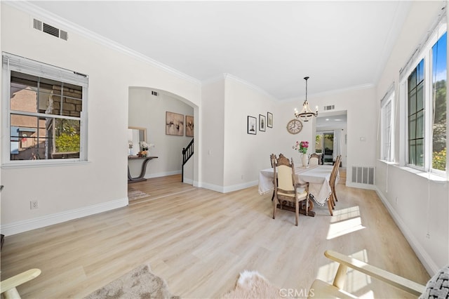 dining space with arched walkways, visible vents, a chandelier, and wood finished floors