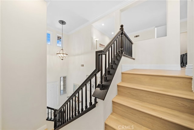 stairway with a notable chandelier, visible vents, crown molding, and a towering ceiling