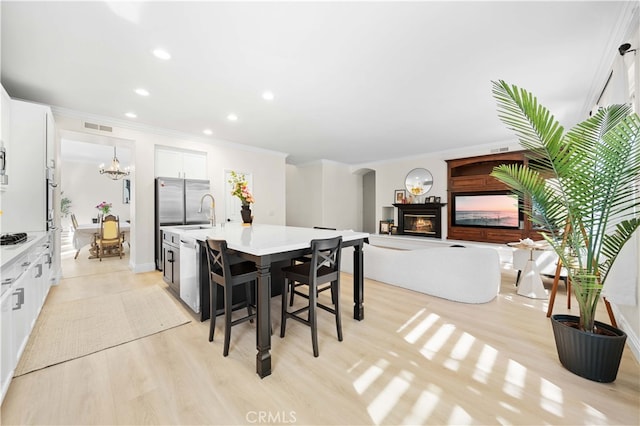 dining space featuring light wood-type flooring, visible vents, arched walkways, and a glass covered fireplace