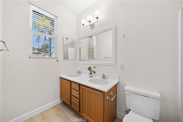 full bathroom featuring double vanity, toilet, baseboards, and a sink