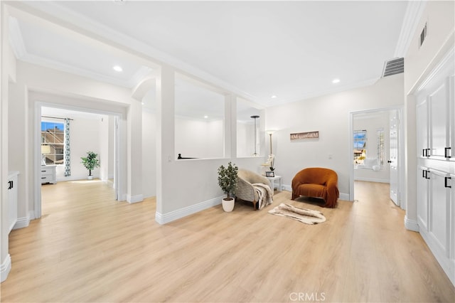 sitting room with visible vents, light wood finished floors, and ornamental molding