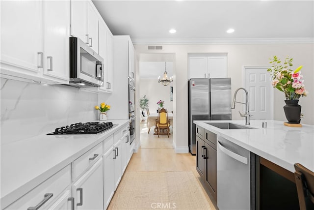 kitchen with white cabinets, ornamental molding, visible vents, and stainless steel appliances