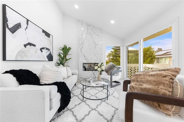 living area featuring vaulted ceiling, recessed lighting, and a high end fireplace