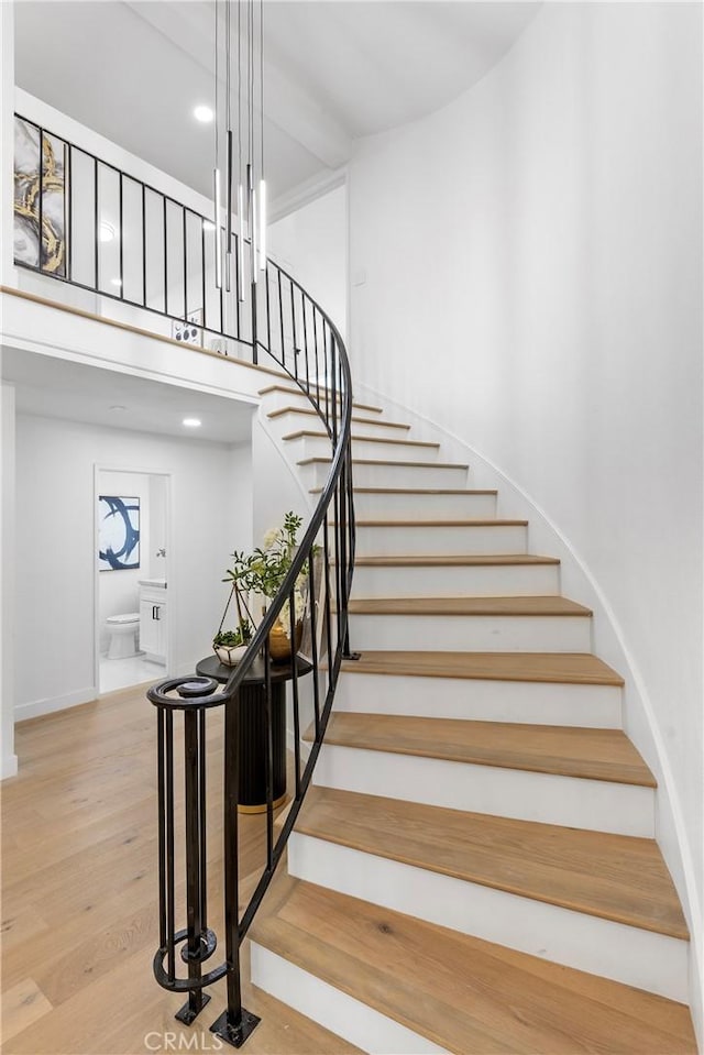 stairs featuring a high ceiling and wood finished floors