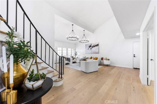 interior space with a chandelier, baseboards, high vaulted ceiling, and wood finished floors