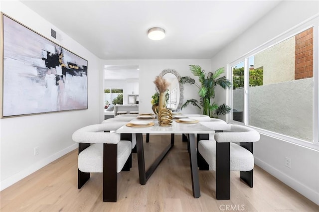 dining room featuring plenty of natural light, baseboards, visible vents, and light wood-type flooring