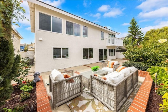 back of house with a patio, an outdoor living space, a balcony, and stucco siding