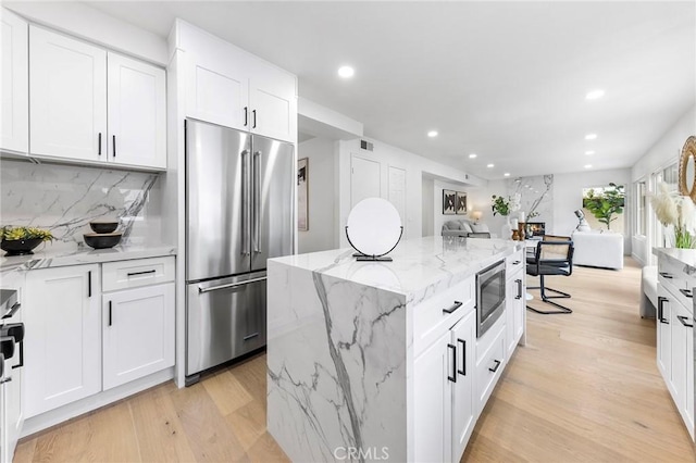 kitchen featuring tasteful backsplash, light wood-style flooring, white cabinetry, and stainless steel appliances