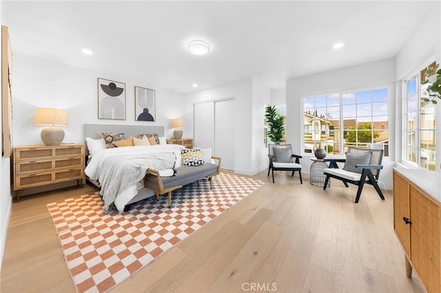 bedroom with recessed lighting, light wood-type flooring, and a closet