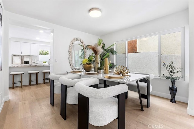 dining space featuring baseboards and light wood finished floors