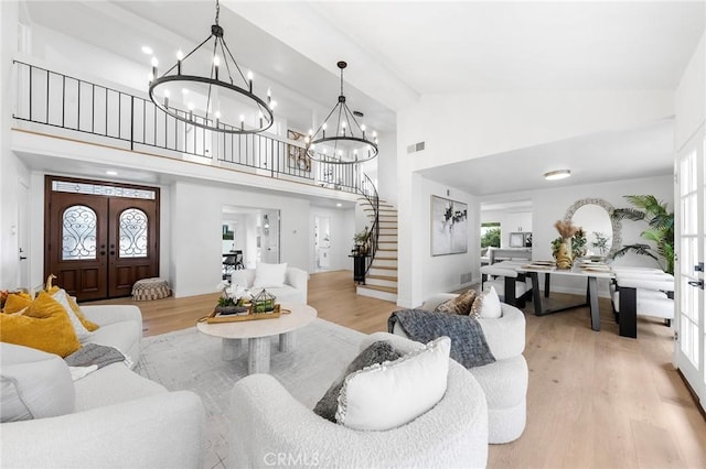 living area featuring stairs, french doors, visible vents, and light wood finished floors