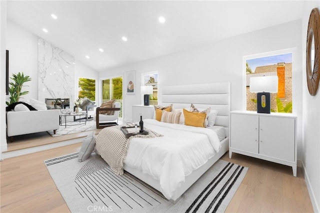 bedroom featuring recessed lighting, lofted ceiling, wood finished floors, and a high end fireplace