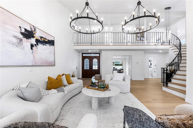 living area with stairway, a notable chandelier, and wood finished floors