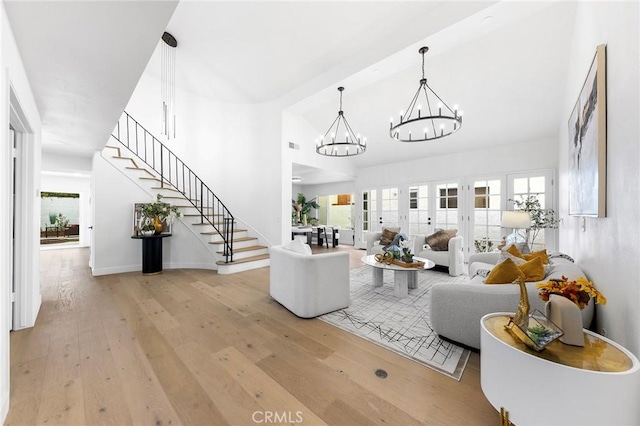 living room featuring stairway, wood-type flooring, baseboards, and a chandelier